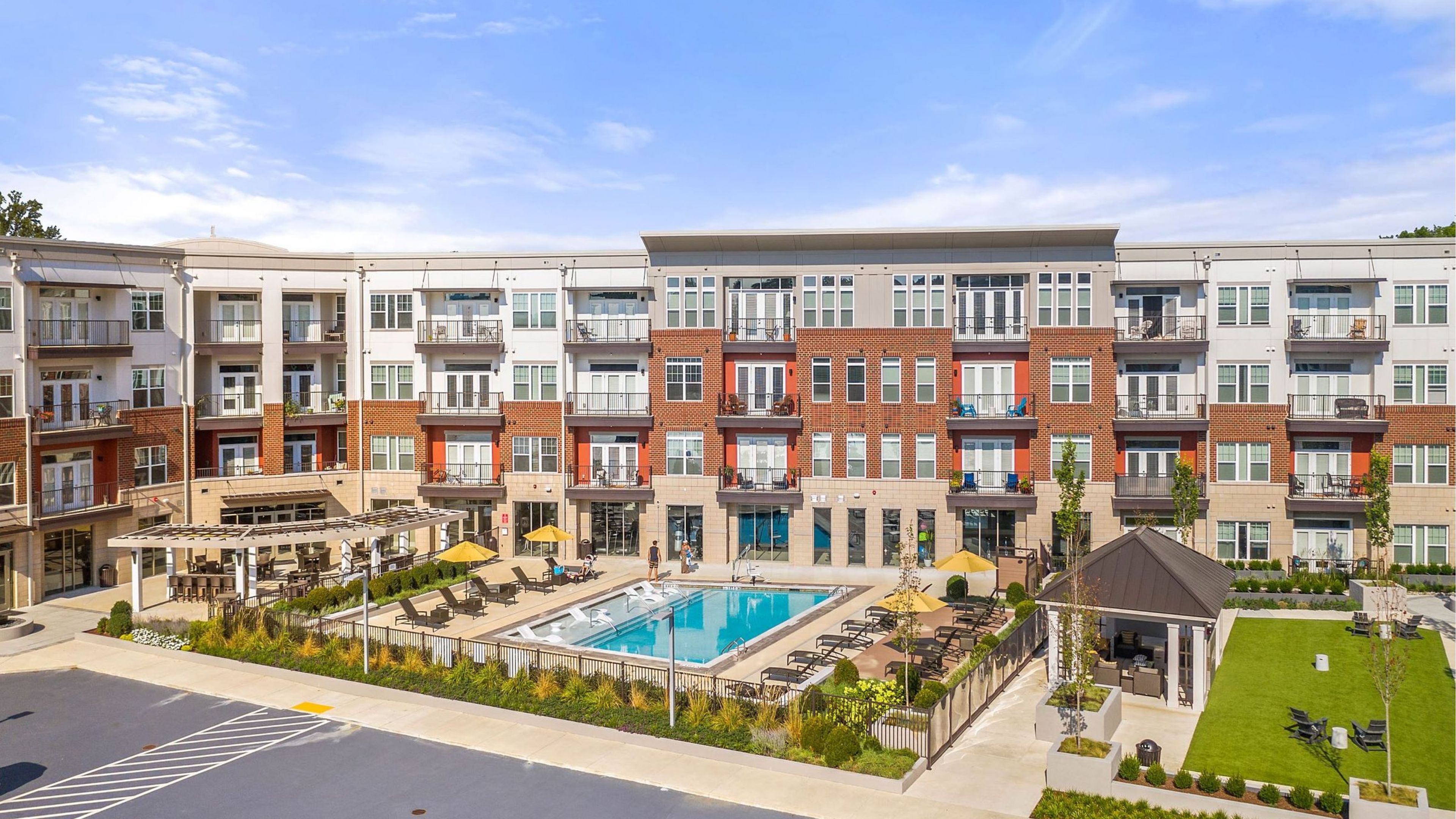 Hawthorne at Friendly apartments community exterior with large green lawn and outdoor pool area